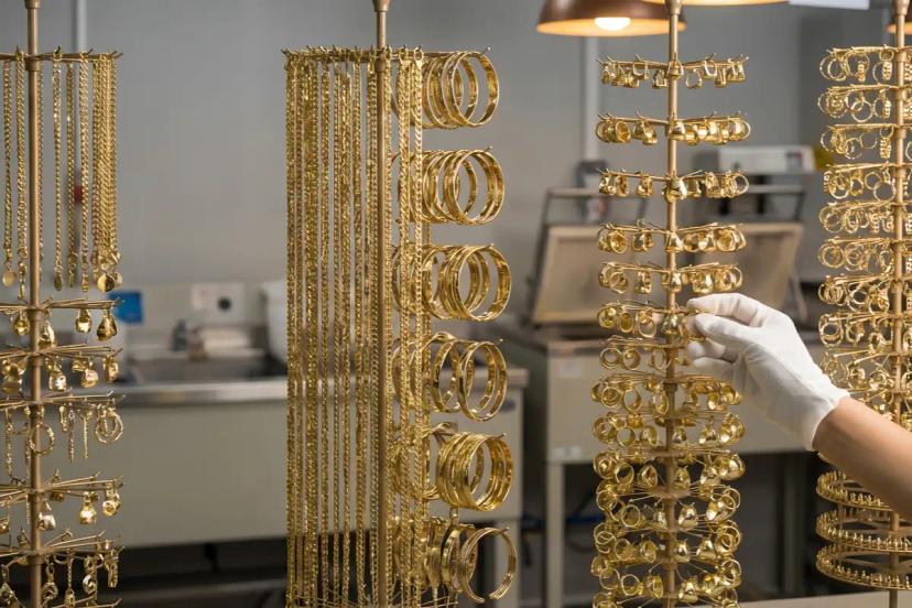Bulk gold tone jewelry hanging racks in a factory finishing area for finish consistency review