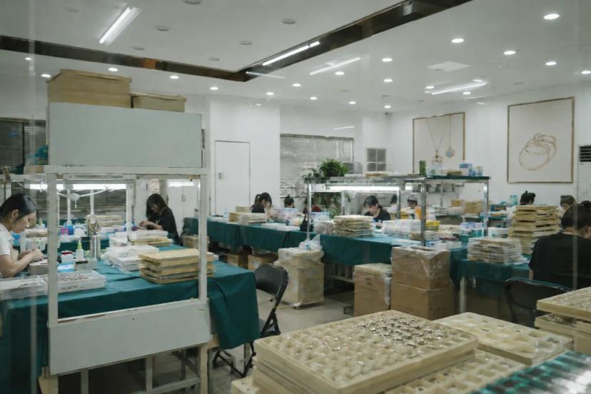 Stainless steel jewelry workshop with organized sample trays and production preparation for jewelry brands